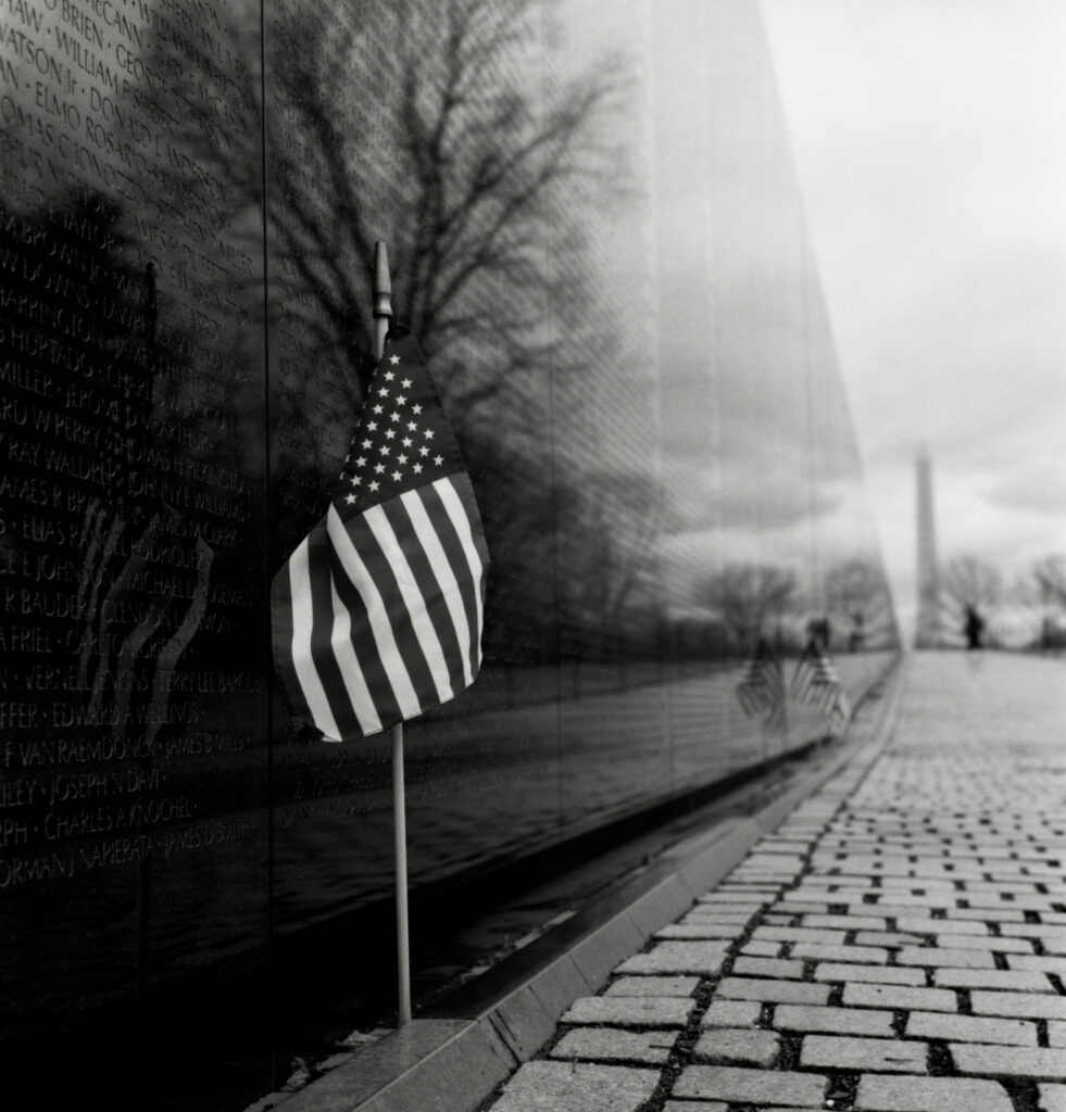 Black and white photo of small american flag at vietnam war memorial in washington dc.