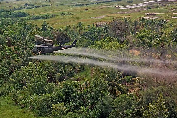 Military helicopter spraying agent orange over dense jungle in vietnam.