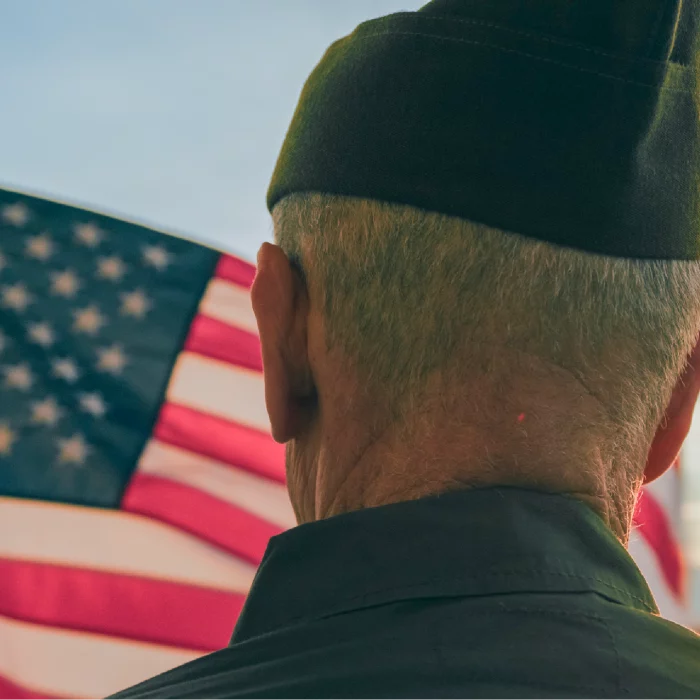 Army veteran looking at us flag.